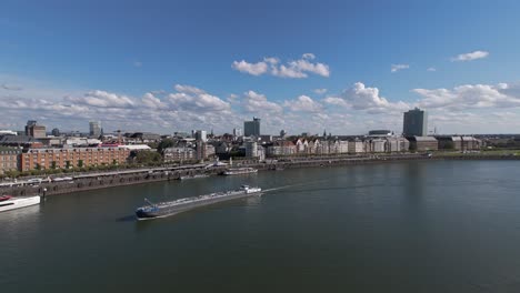 Toma-De-Seguimiento-Panorámica-Con-Drones-De-Gran-Angular-De-Una-Barcaza-En-El-Centro-Del-Rin,-Dusseldorf,-Alemania