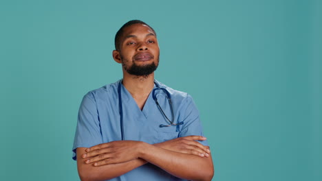 portrait of joyful male nurse standing with arms folded