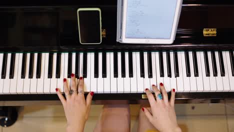 a person's hands playing a piano with a tablet displaying sheet music