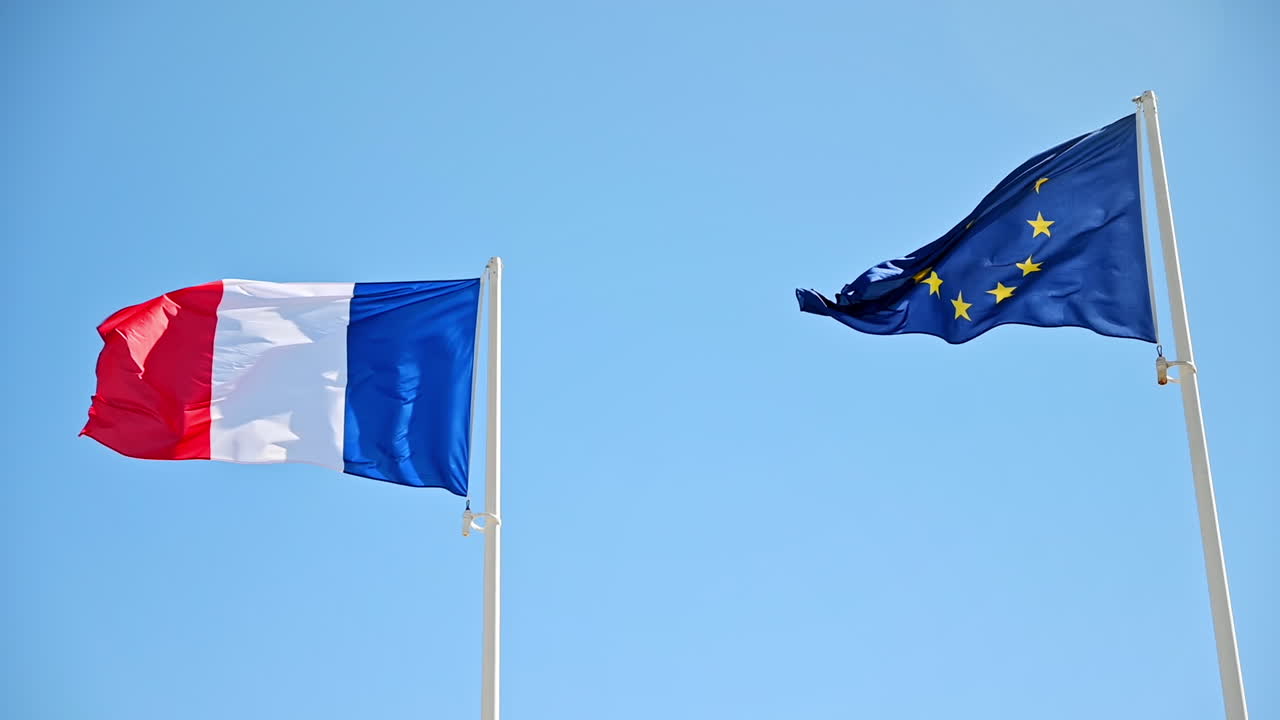 Bandiere francesi e dell'UE che sventolano al vento su pennoni. Cielo blu sullo sfondo. Movimento al rallentatore