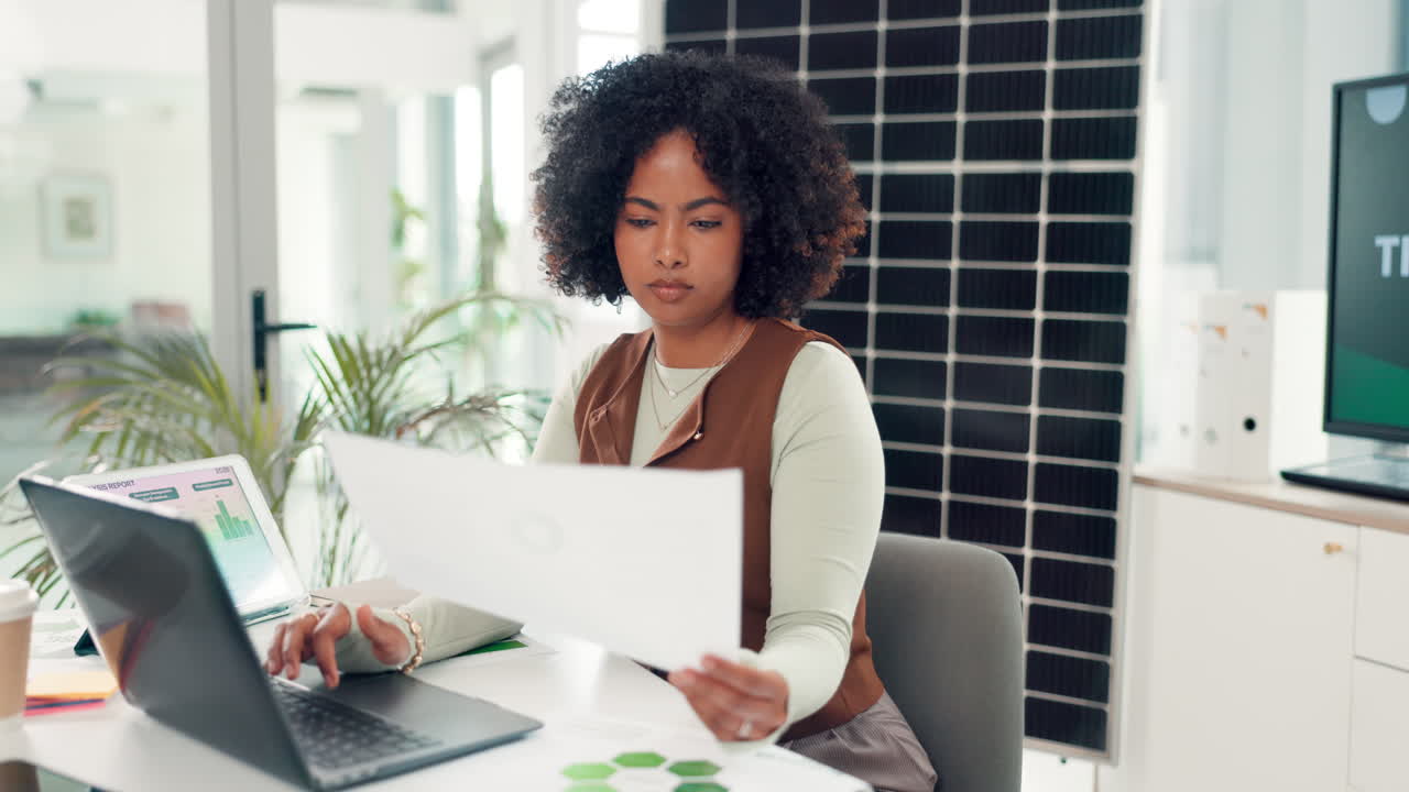 Donna concentrata che lavora su laptop e documenti in un ufficio moderno
