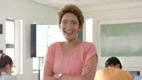 smiling teacher standing in classroom with students studying in background at high school