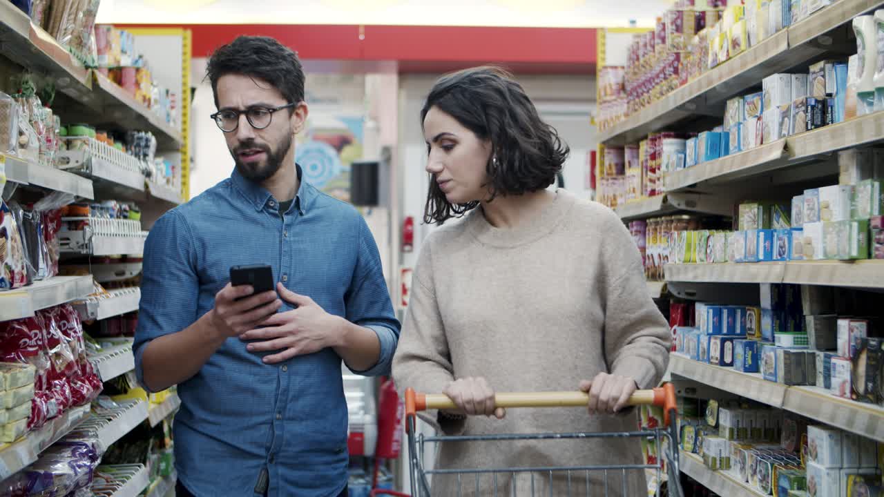 pareja usando un teléfono inteligente en la tienda de comestibles