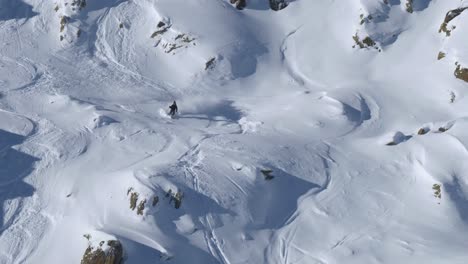 Following-a-slalom-skier-riding-down-rocky,-powder-snow-slopes-of-the-Alps-of-Tyrol