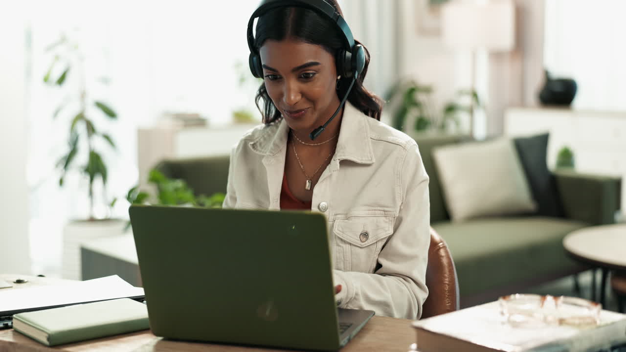 Woman working on laptop with headset at home office