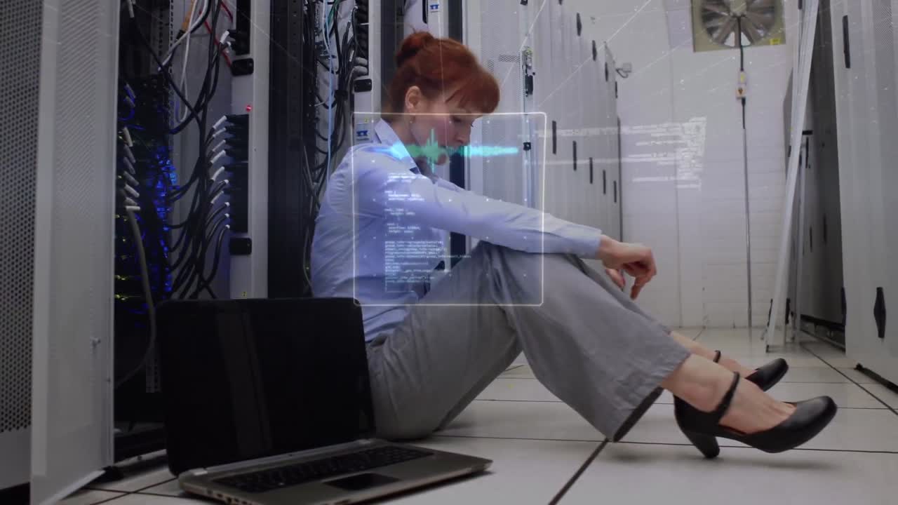 Mehrere Bildschirme mit Datenverarbeitung vor einer kaukasischen Ingenieurin, die in einem Serverraum sitzt.