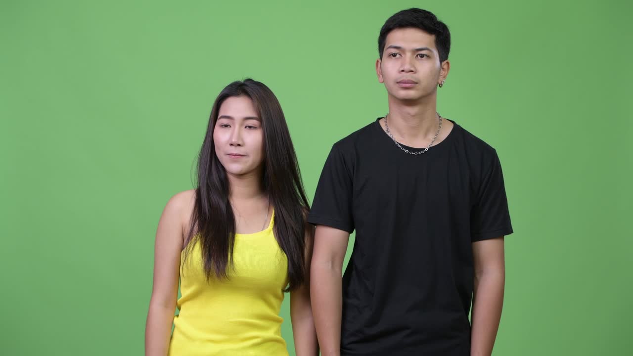 Young Asian couple giving thumbs up together