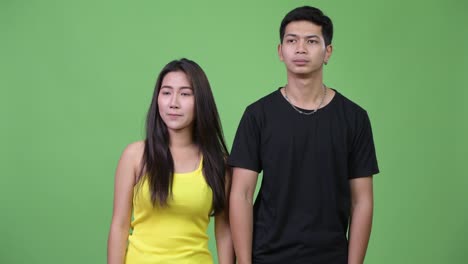 young asian couple giving thumbs up together