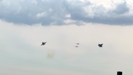 three f-22 raptors execute synchronized aerial maneuvers against a cloudy sky during the avalon airshow in geelong, australia