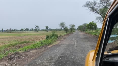 POV-shot-of-a-yellow-taxi-travelling-in-a-broken-muddy-road-in-a-Indian-village