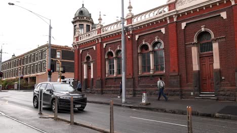 bus and car passing historic red brick building