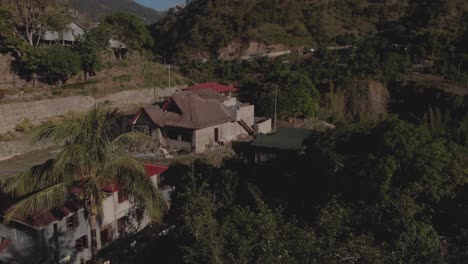 aerial flying away from three men standing on the deck top floor of unfinished building house in a third world country kabayan, benguet, philippines revealing the entire village
