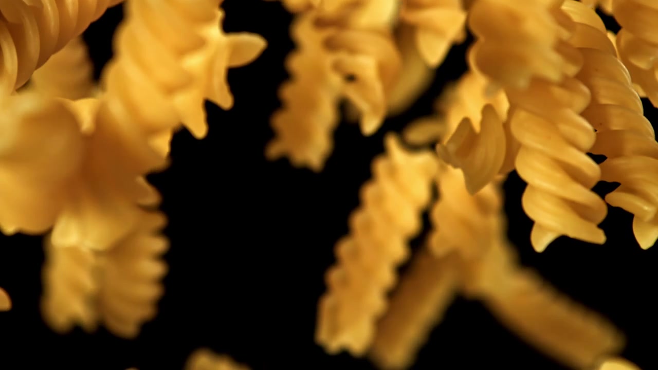 Fusilli Pasta Falling and Rising in Slow Motion on Black Background