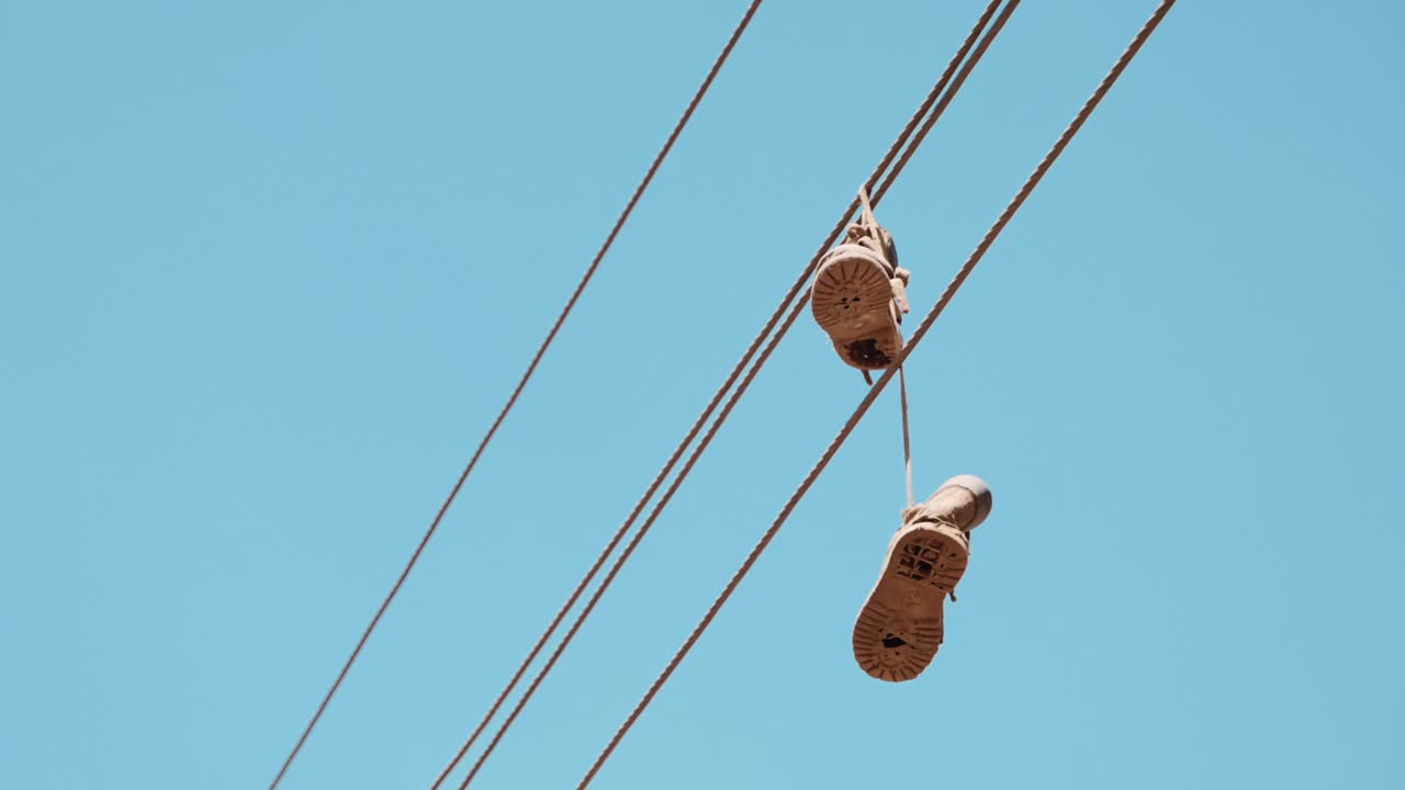 ⁇ 은 운동화가 와이어를  ⁇ 고  ⁇ 에 매달려 있습니다.