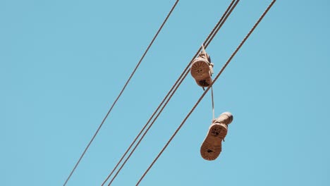 old sneakers dangling by their laces over a wire