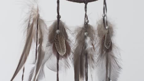 hanging feathers from dreamcatcher swaying side to side against plain white background