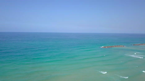 sunny summer aerial in israel, ashkelon beach - flyby to the ocean over rock dams