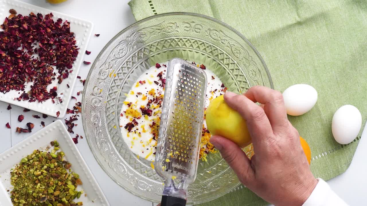 Preparazione di un dolce chiamato Torta dell'Amore Persiana, fatta con petali di rosa e pistacchi. Torta con glassa bianca. Mescolare la scorza di limone nell'impasto. Bella torta per l'ora del tè o una celebrazione.