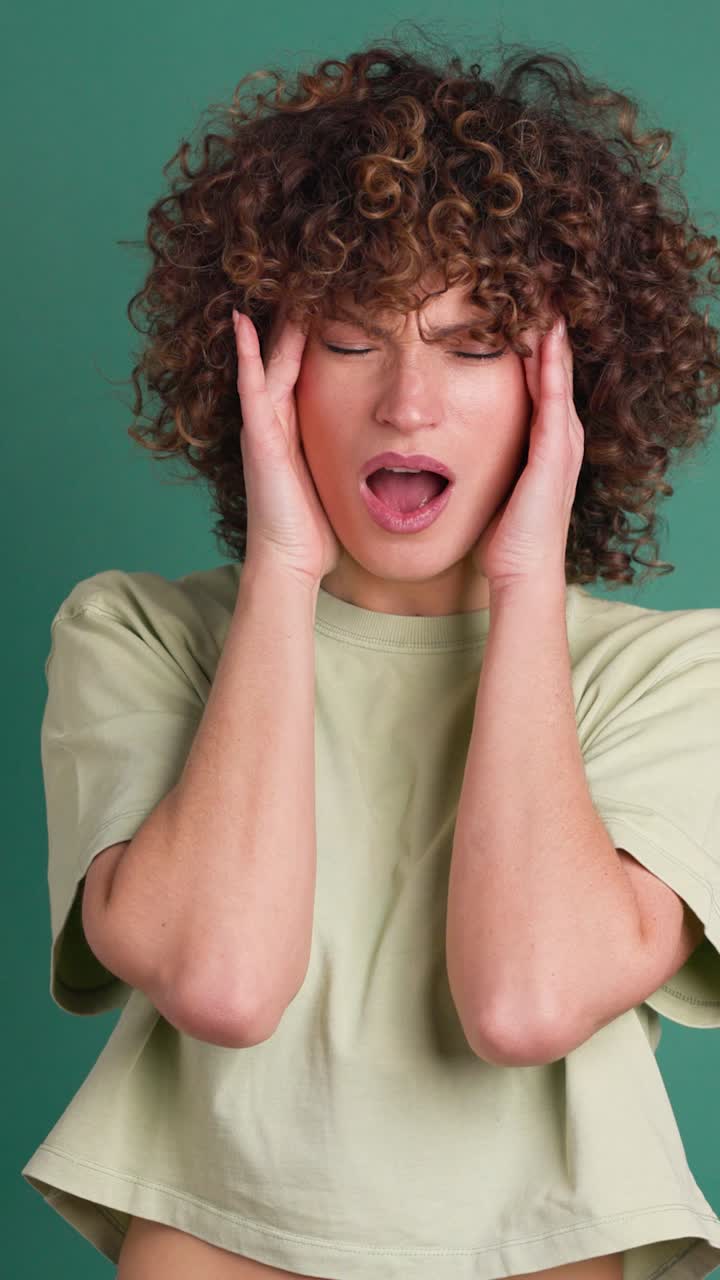 Adult woman with her hands on her head because of a headache. Vertical orientation