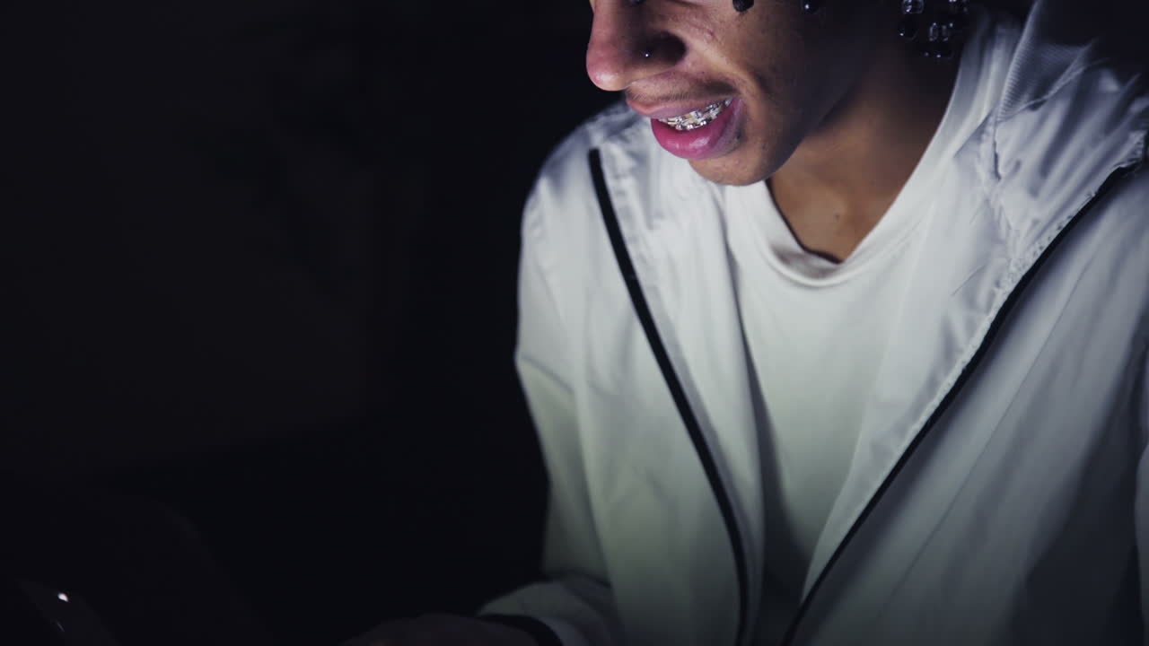 retrato de un adolescente sonriente usando una computadora portátil por la noche
