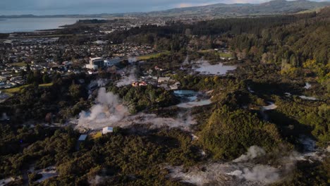 Aerial-panoramic-pull-back-of-beautiful-scenery-of-Te-Puia-geothermal-preserve