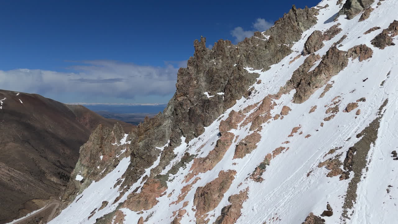la nieve cubre las laderas rocosas de cerro la hoya en esquel, chubut, argentina, en un día soleado, ofreciendo vistas impresionantes de las montañas de los andes.