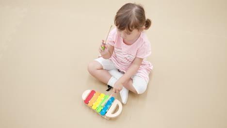 child playing on xylophone sitting on a floor at home - high angle view