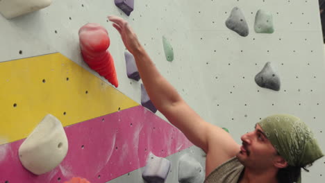 man climbing on artificial bouldering wall in indoor gym