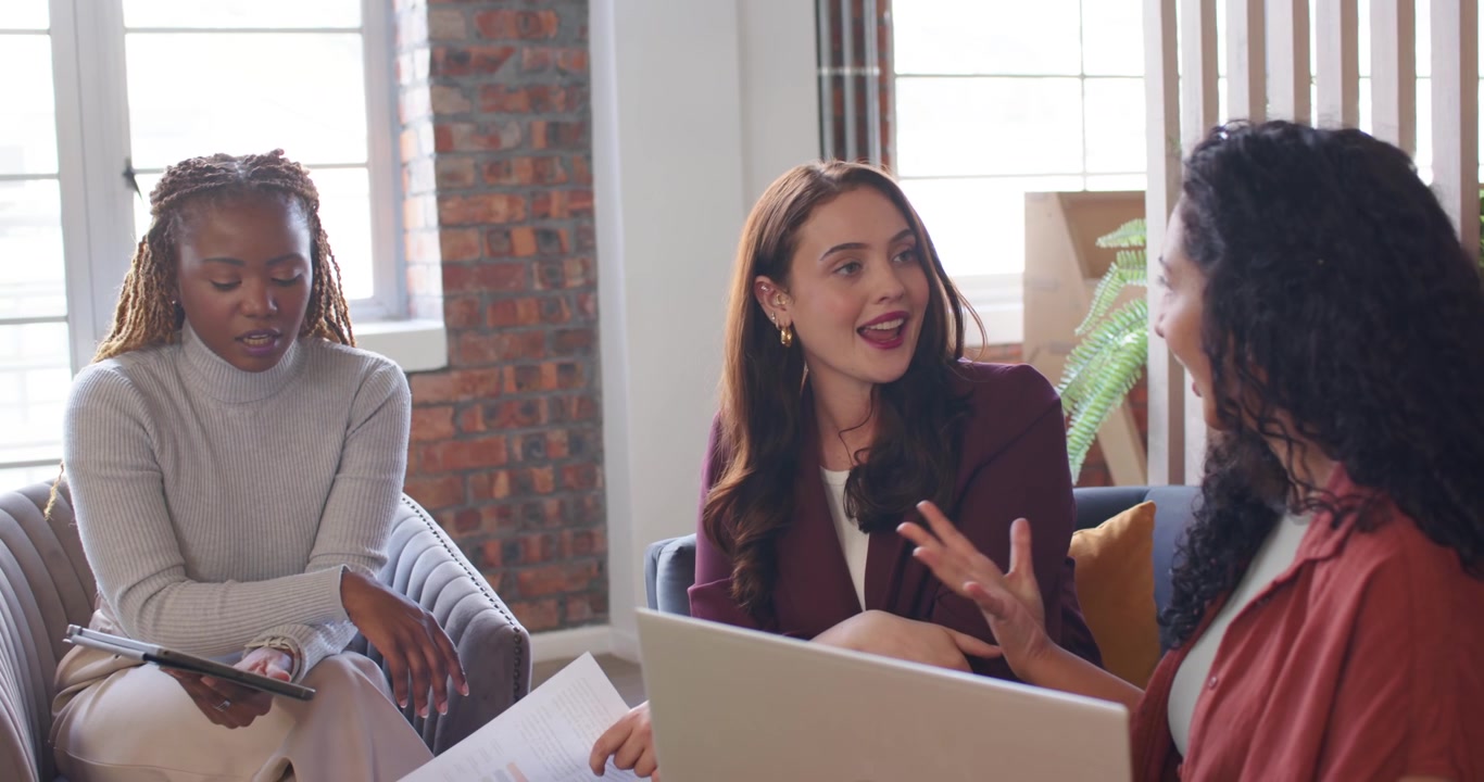 Diverse female team shifting as lead woman explaining charts at lounge reviewing laptop to decide
