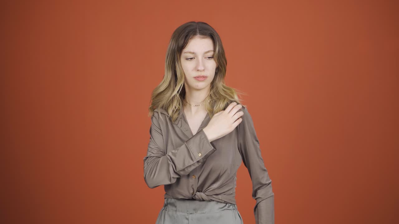 카메라를 바라보는 젊은 여성은 가려움증이 있습니다.