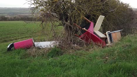 office furniture illegally fly tipped into a hedge on a uk rural roadside