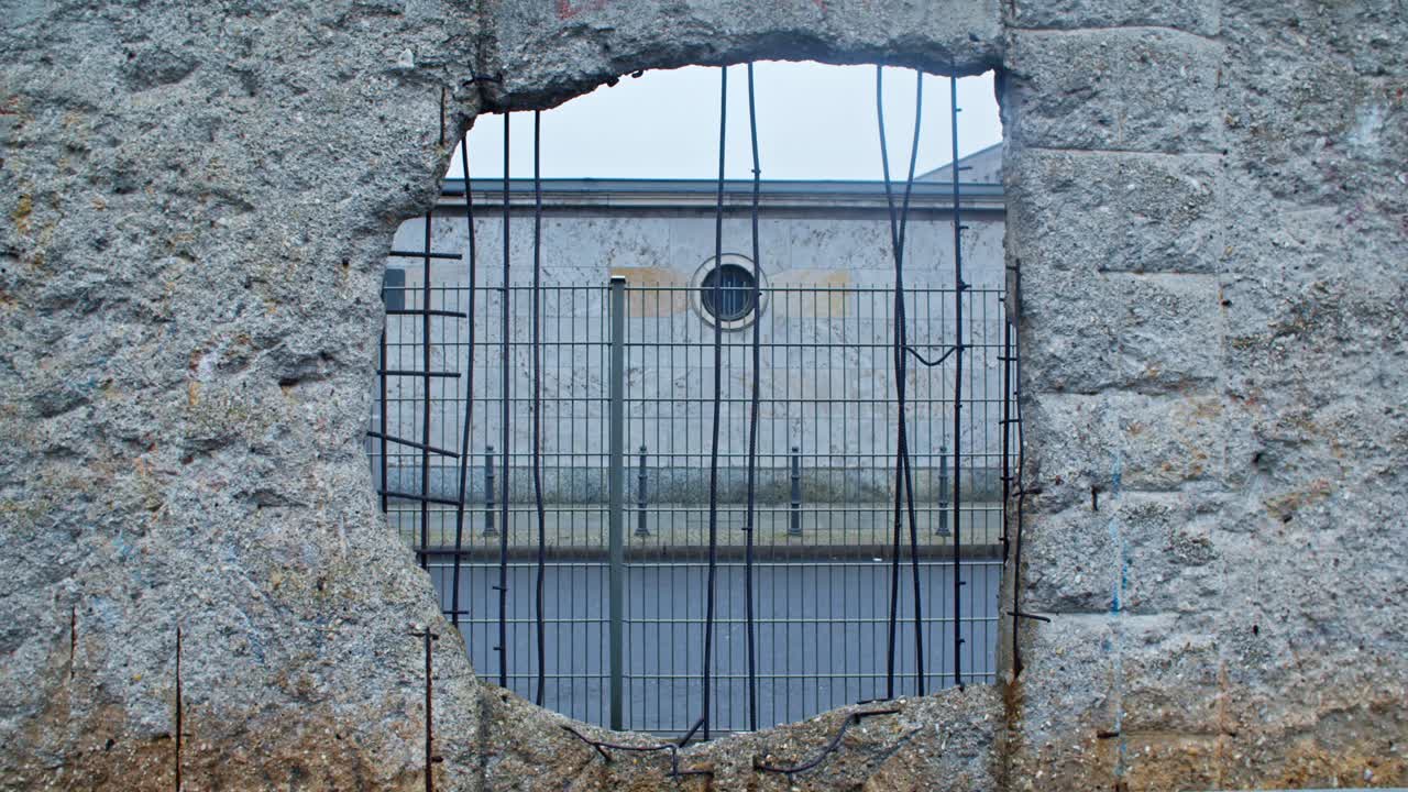 Remainings of Berlin Wall hole with car passing by in Baudenkmal Berliner Mauer