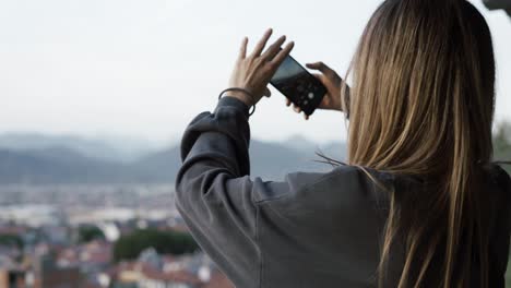 Woman-take-a-photo,-blurred-city-hills-panorama-on-background