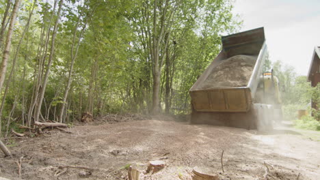 Dump-truck-dumping-tipping-gravel-for-garage-floor-build-in-countryside