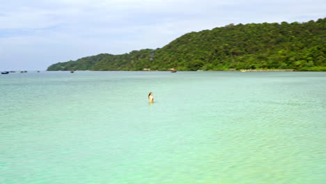 aerial tracking shot of female model swimming on beautiful beach.