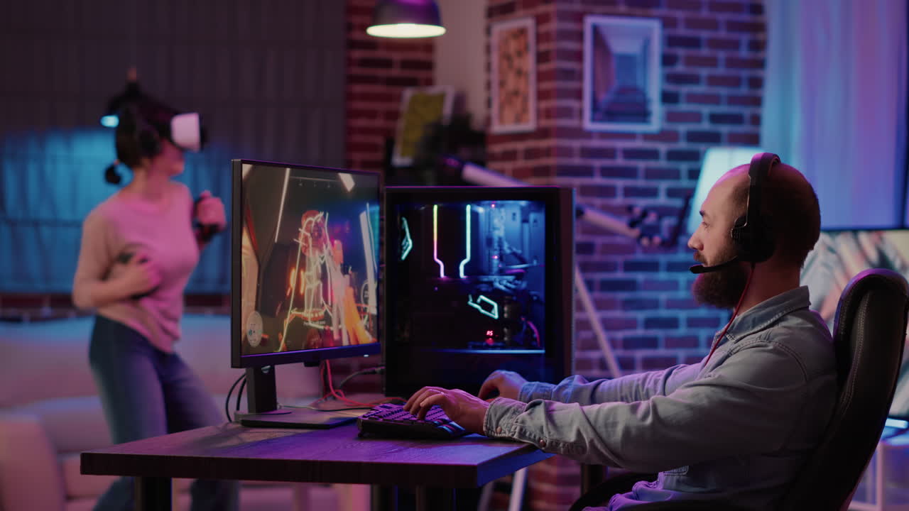 Static tripod shot of gamer playing multiplayer first person shooter on pc while gaming girl is fighting in virtual reality