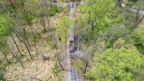 an aerial view of an 1860's steam passenger train traveling thru a wooded area on a lonely single track