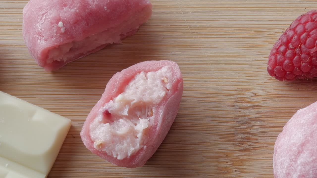 Soft pink mochi filled with strawberry and white chocolate, sliced open to reveal the creamy filling