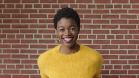 portrait-of-confident-african-american-woman-smiling-cheerful-wearing-yellow-jersey-on-brick-wall-background