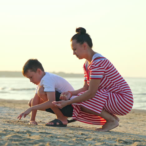 boy with his mother on a sand beach in the evening. young woman playing with her son on the beach by the sea.