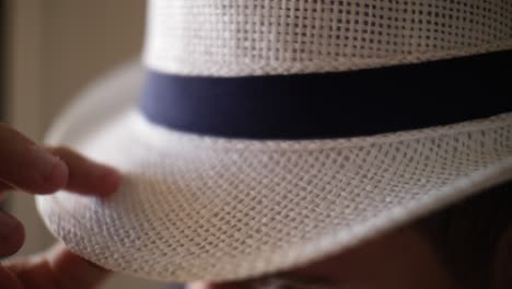 slow motion close-up of a man running his hands over the brim of his hat