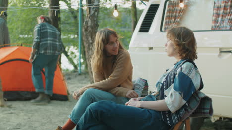 Cheerful-Girlfriends-Chatting-by-Van-at-Campsite