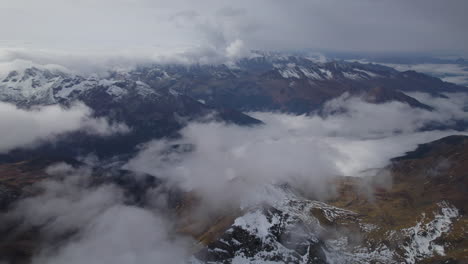 Aerial-high-angle-shot-above-snowy-mountains-and-clouds-of-Austria-during-daytime