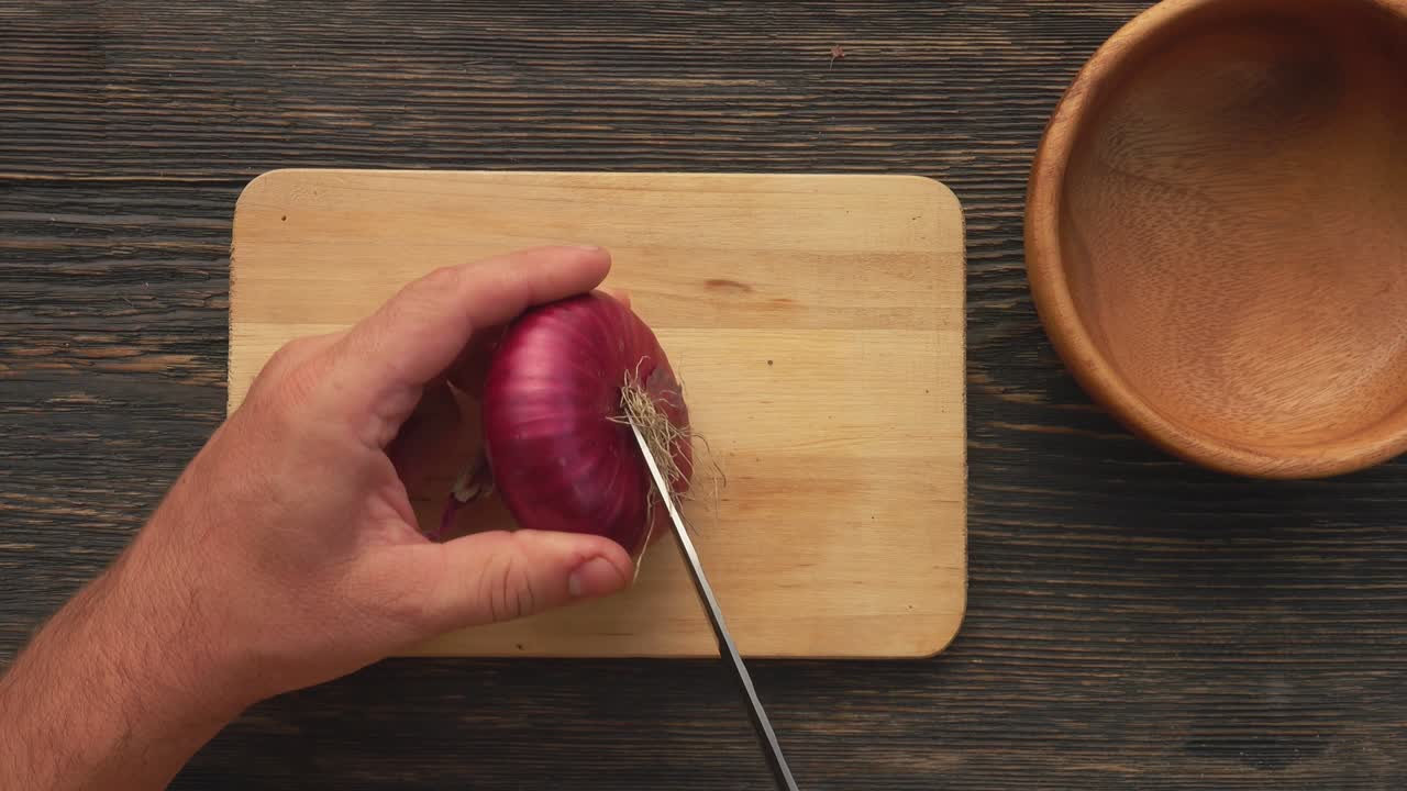 vista superior de las manos masculinas cortando anillos de cebolla roja en la tabla de madera