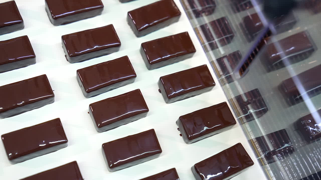 Manufacture of chocolate bars. Ready-made candies move along the conveyor belt. Sweet desserts enterprise. Close up.