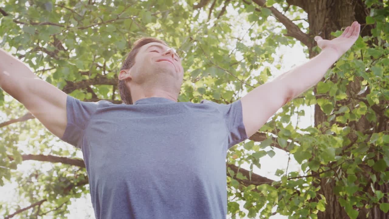 피트니스 옷을 입고 야외에서 팔을 펴고 자연을 축하하는 남자