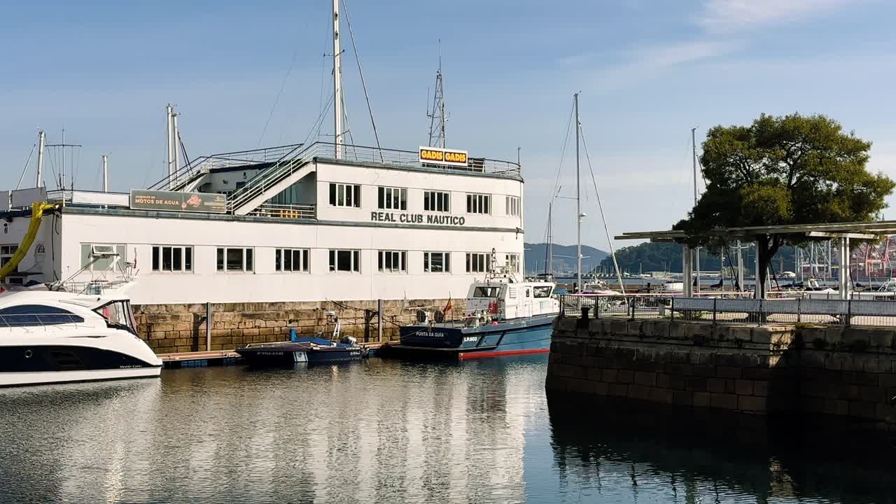 Real Club Náutico building with docked boats reflecting on the calm harbor waters in Vigo Spain