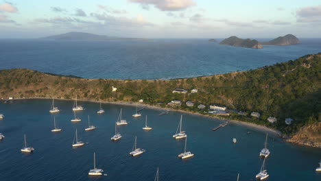 aerial: british virgin islands - cooper island - drone shot backward revealing moored yachts at sunset