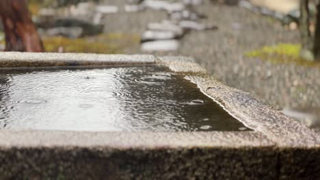 Gotas-De-Lluvia-Cayendo-Sobre-Un-Lavabo-De-Piedra-Fuera-Del-Templo-Nanzen-ji-En-Kioto,-Japón