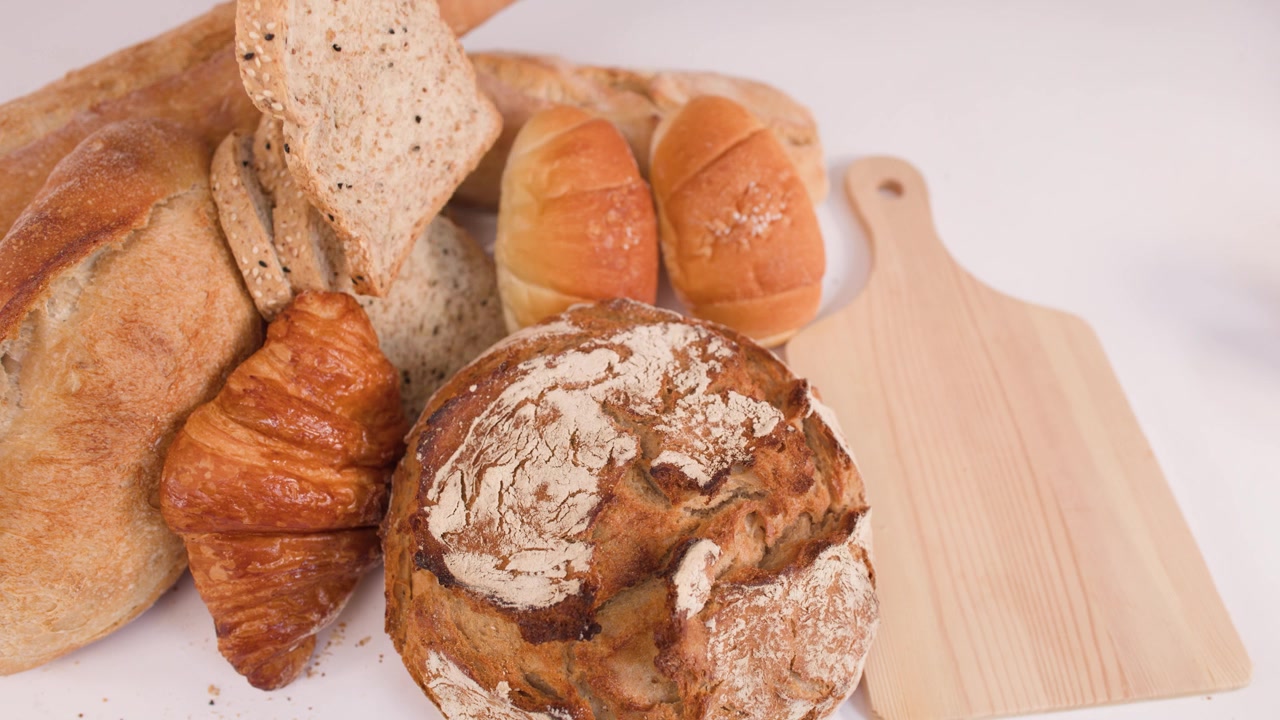 Hand Placing Slice of Whole Grain Bread on Wooden Board